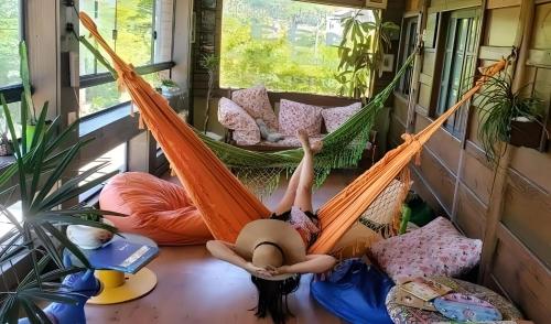 a woman laying in a hammock in a tiny house at Joaquina 433 - Pousada Floripa in Florianópolis