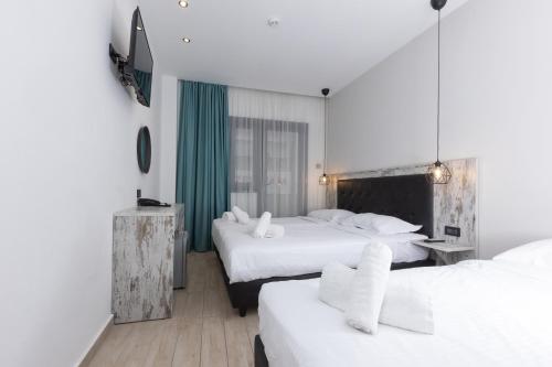 una camera d'albergo con due letti con lenzuola bianche di Evita Asty ad Atene