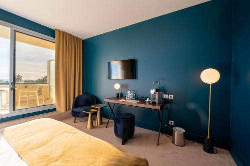a bedroom with blue walls and a desk and a bed at Casino Hôtel des Palmiers in Hyères