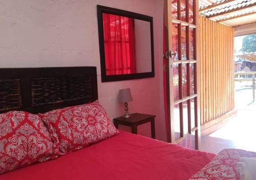 een slaapkamer met een bed met een rode sprei en een raam bij Perdehoek Venue in Lichtenburg