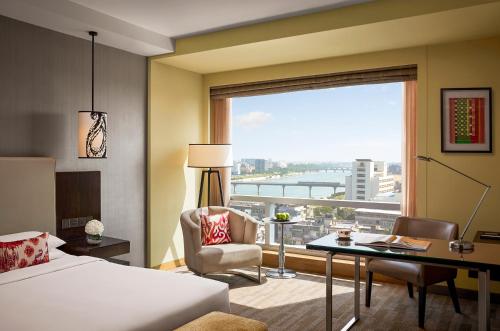 a hotel room with a bed and a desk and a window at Hyatt Regency Ahmedabad in Ahmedabad