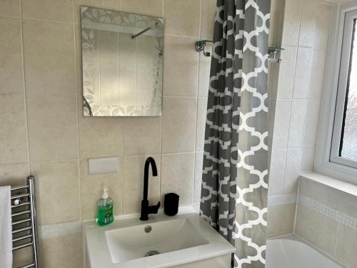 a bathroom with a sink and a shower curtain at Pass the Keys Stylish Family Friendly 3 Bed home with Parking in Bushey