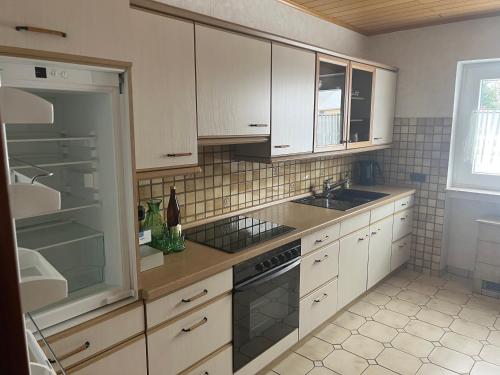 een keuken met witte kasten, een wastafel en een fornuis bij Ferienwohnungjahrsfeld in Straßenhaus