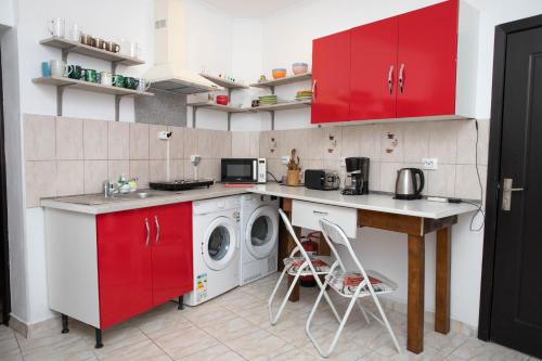 - une cuisine avec des placards rouges et un lave-linge dans l'établissement Cosy apartment in city centre, à Oradea