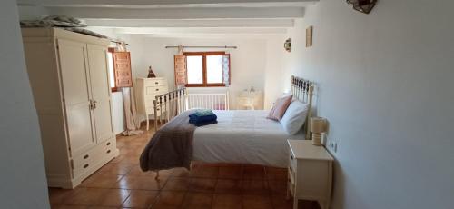 a bedroom with a white bed and a wooden floor at Villa Ugijar in Ugíjar
