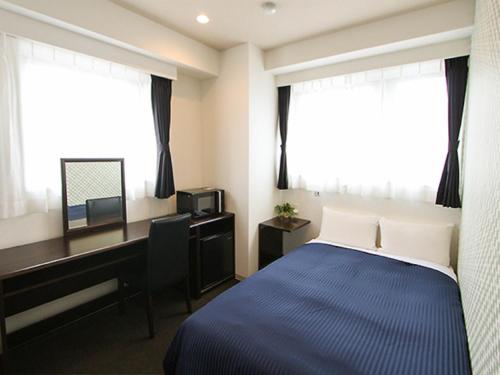 a bedroom with a bed and a desk and a computer at HOTEL LiVEMAX Asakusa Sky Front in Tokyo