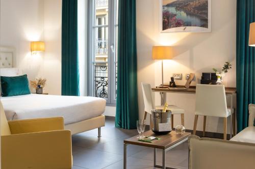 a hotel room with a bed and a desk at Hôtel Nice Azur Riviera in Nice