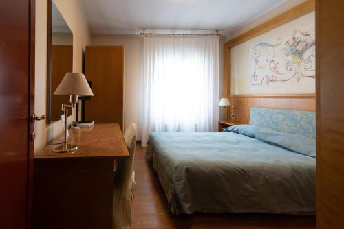 a bedroom with a bed and a desk and a window at Residence La Fenice in Padova