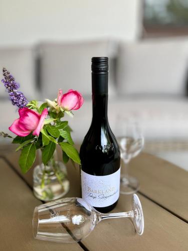 a bottle of wine sitting on a table with glasses at Barkland Apartman in Tarcal