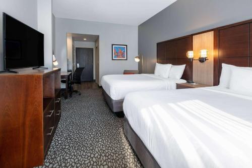 a hotel room with two beds and a flat screen tv at Wingate by Wyndham - DFW North in Irving