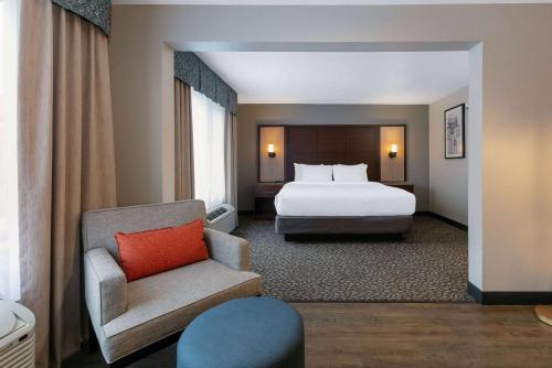 a hotel room with a bed and a chair at Wingate by Wyndham - DFW North in Irving