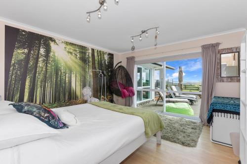 - une chambre avec un lit blanc orné d'une fresque murale représentant des arbres dans l'établissement Green View - Parua Bay Holiday Home, à Parua Bay