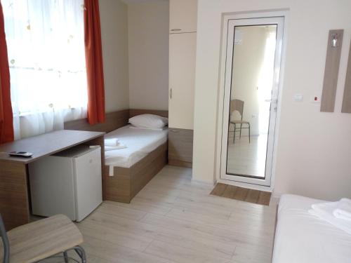 a small room with a bed and a desk and a mirror at Хостел Атлас - Hostel Atlas in Blagoevgrad