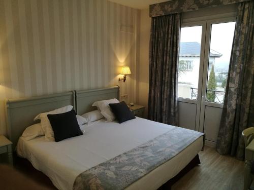 een slaapkamer met een bed en een groot raam bij Hotel PAX Torrelodones in Torrelodones