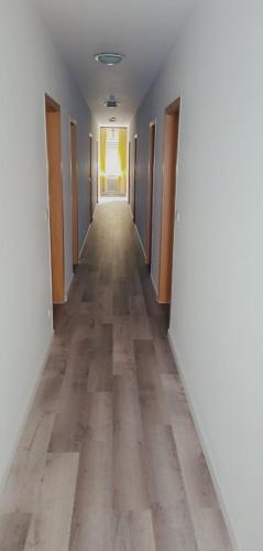 un pasillo de una habitación vacía con puertas y suelo de madera en Hotel & Restaurant Dalmacija Polch, en Polch