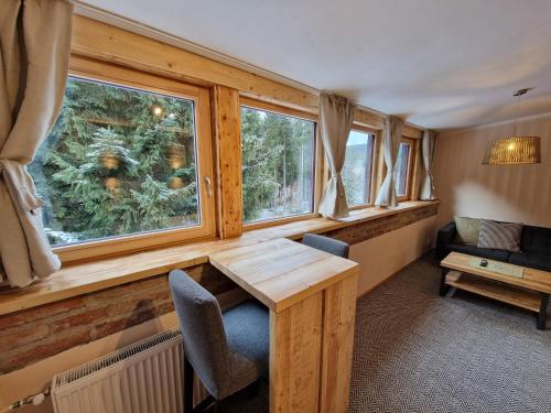 a room with a wooden table and two windows at Pension Linda in Harrachov