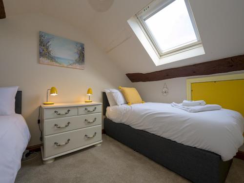 a bedroom with two beds and a window at Pass the Keys Porth Vaynor Farmhouse and Gardens in Usk