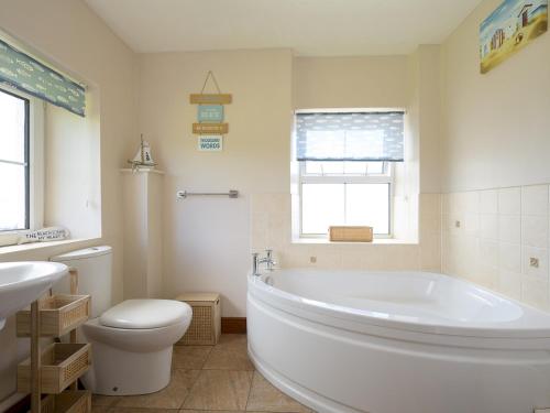 a bathroom with a tub and a toilet and a sink at Pass the Keys Porth Vaynor Farmhouse and Gardens in Usk