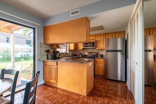 a kitchen with wooden cabinets and a stainless steel refrigerator at Amazing 2 Bedroom Townhouse near beach in Indialantic