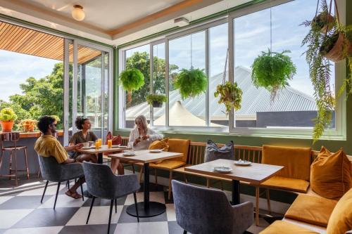 Leute sitzen an Tischen in einem Restaurant mit großen Fenstern in der Unterkunft Cloud 9 Boutique Hotel and Spa in Kapstadt