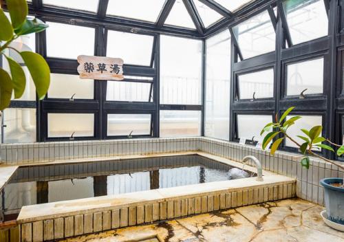 une baignoire dans une serre avec une piscine d'eau dans l'établissement HOTEL LiVEMAX Kofu, à Kai