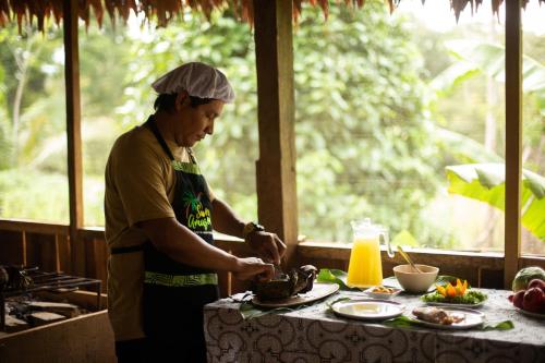 Yucuruche的住宿－Eywa Lodge Amazonas - All inclusive，坐在厨房里餐桌上准备食物的人