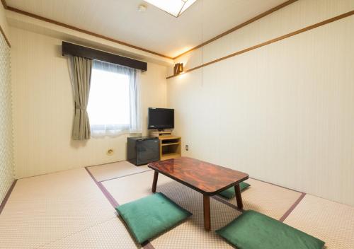a room with a table and two green chairs at HOTEL LiVEMAX Kofu in Kai