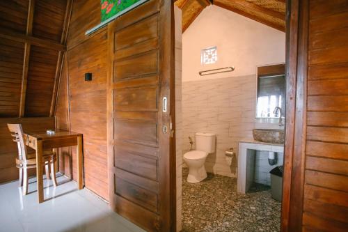 a bathroom with a toilet and a table and a sink at JUN COTTAGE in Toyapakeh