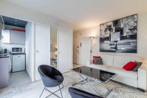 ein Wohnzimmer mit einer weißen Couch und einem Stuhl in der Unterkunft Cozy studio in the heart of Cannes - Near sea in Cannes