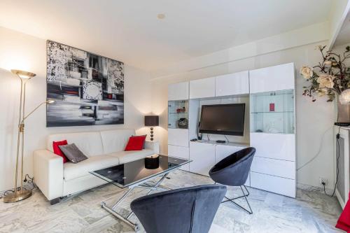 ein Wohnzimmer mit einem weißen Sofa und einem TV in der Unterkunft Cozy studio in the heart of Cannes - Near sea in Cannes