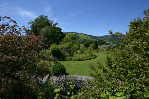 a garden with trees and flowers in the foreground at Pentre Cerrig Country House in Llanferres