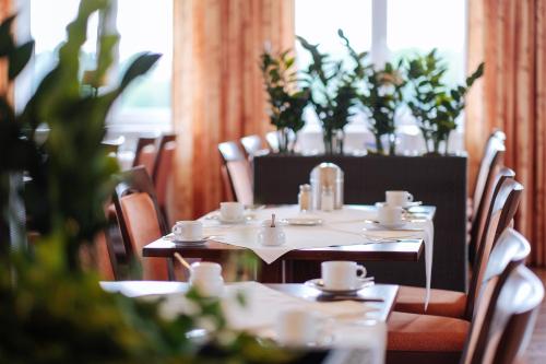 a dining room with tables and chairs and plants at Bernsteinsee Hotel&Ferien in Sassenburg