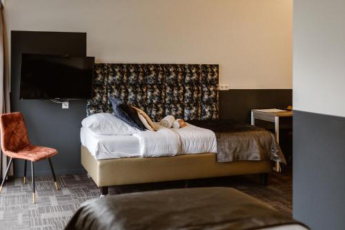 a hotel room with a bed and a flat screen tv at Hotel Torpedoloods in Hoek van Holland