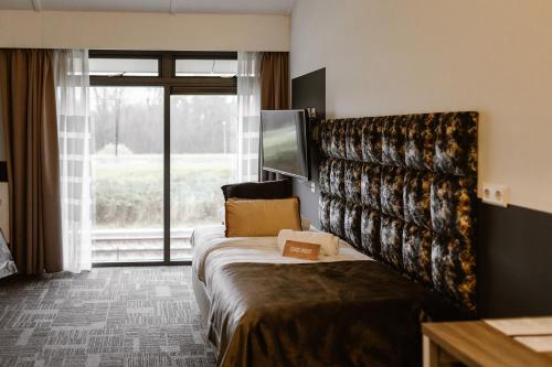 a hotel room with a bed and a large window at Hotel Torpedoloods in Hoek van Holland