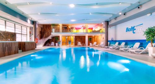 a large swimming pool in a hotel with white chairs at Apartament na Klifowej in Niechorze