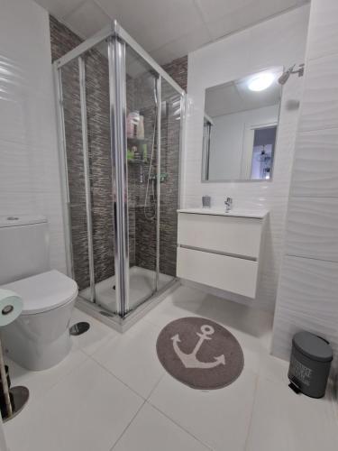 La salle de bains est pourvue d'une douche, de toilettes et d'un tapis. dans l'établissement Apartamento Calpe Beach 1, à Calp