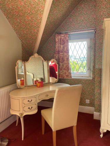 a dressing table with a mirror and a chair at Pentre Cerrig Country House in Llanferres