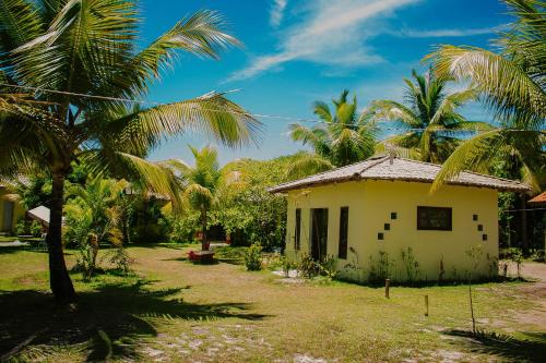 a small house in a yard with palm trees at Pousada Vida Mar in Barra Grande