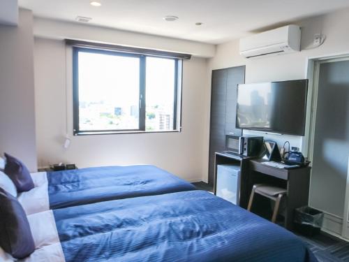 a hotel room with a bed and a flat screen tv at HOTEL LiVEMAX Takadanobaba Ekimae in Tokyo