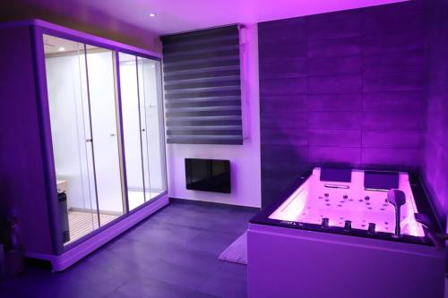 um quarto roxo com uma banheira e uma janela em NARCISSE Balnéo, Sauna, Hammam em Reims