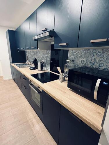 une cuisine avec des armoires noires et un comptoir en bois dans l'établissement NARCISSE Balnéo, Sauna, Hammam, à Reims