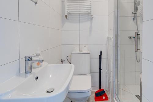 a white bathroom with a toilet and a sink at Pod Winogronem - Apartamenty z basenem i wyżywieniem in Pobierowo