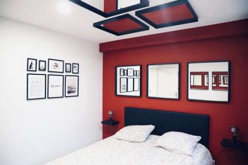 um quarto com uma parede vermelha com uma cama e espelhos em NARCISSE Balnéo, Sauna, Hammam em Reims