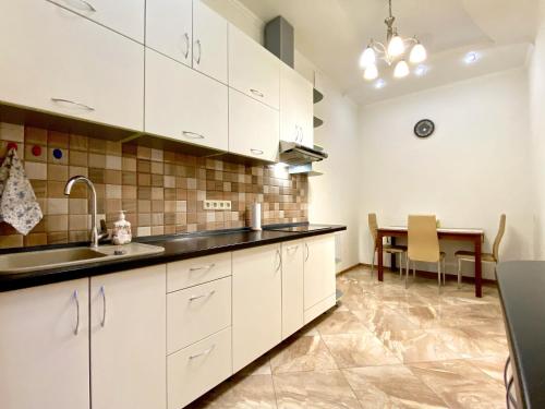 una cocina con armarios blancos y una mesa. en Чарівна, простора квартира в 2хв від МВЦ, Лівобережна, en Kiev