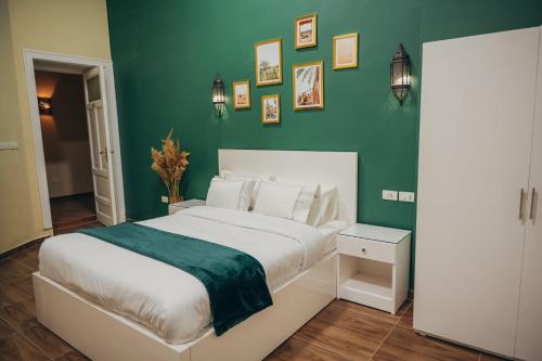 een slaapkamer met een groot bed met een groene muur bij Hathor House in Caïro