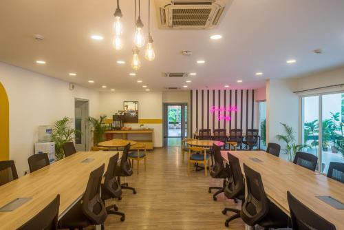 a cafeteria with wooden tables and chairs and a dining room at Olive Magrath - By Embassy Group in Bangalore