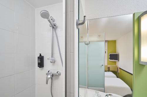 een badkamer met een douche en een spiegel bij ibis budget Wrocław Południe in Wrocław