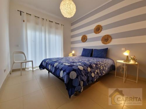 1 dormitorio con cama azul y pared a rayas en Casa dos Peixinhos T1 by YHA, en Conceição
