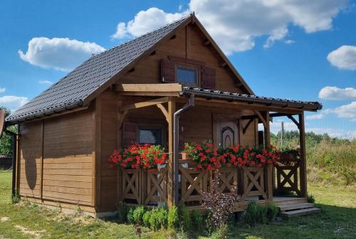 a small wooden cabin with flowers in the window at Domek Triftberg in Chojna