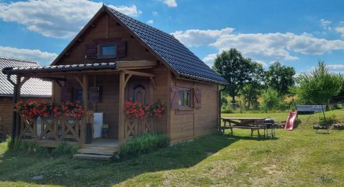 a small wooden shed with a table and flowers at Domek Triftberg in Chojna